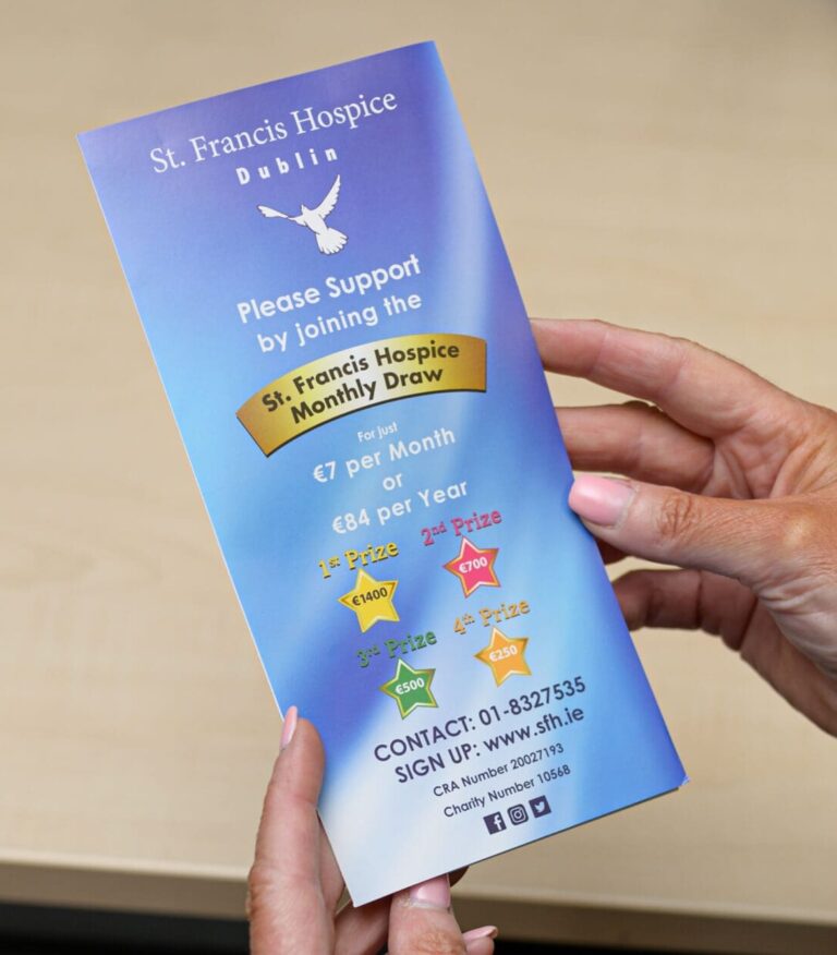 woman holds a leaflet with information about the hospice monthly draw